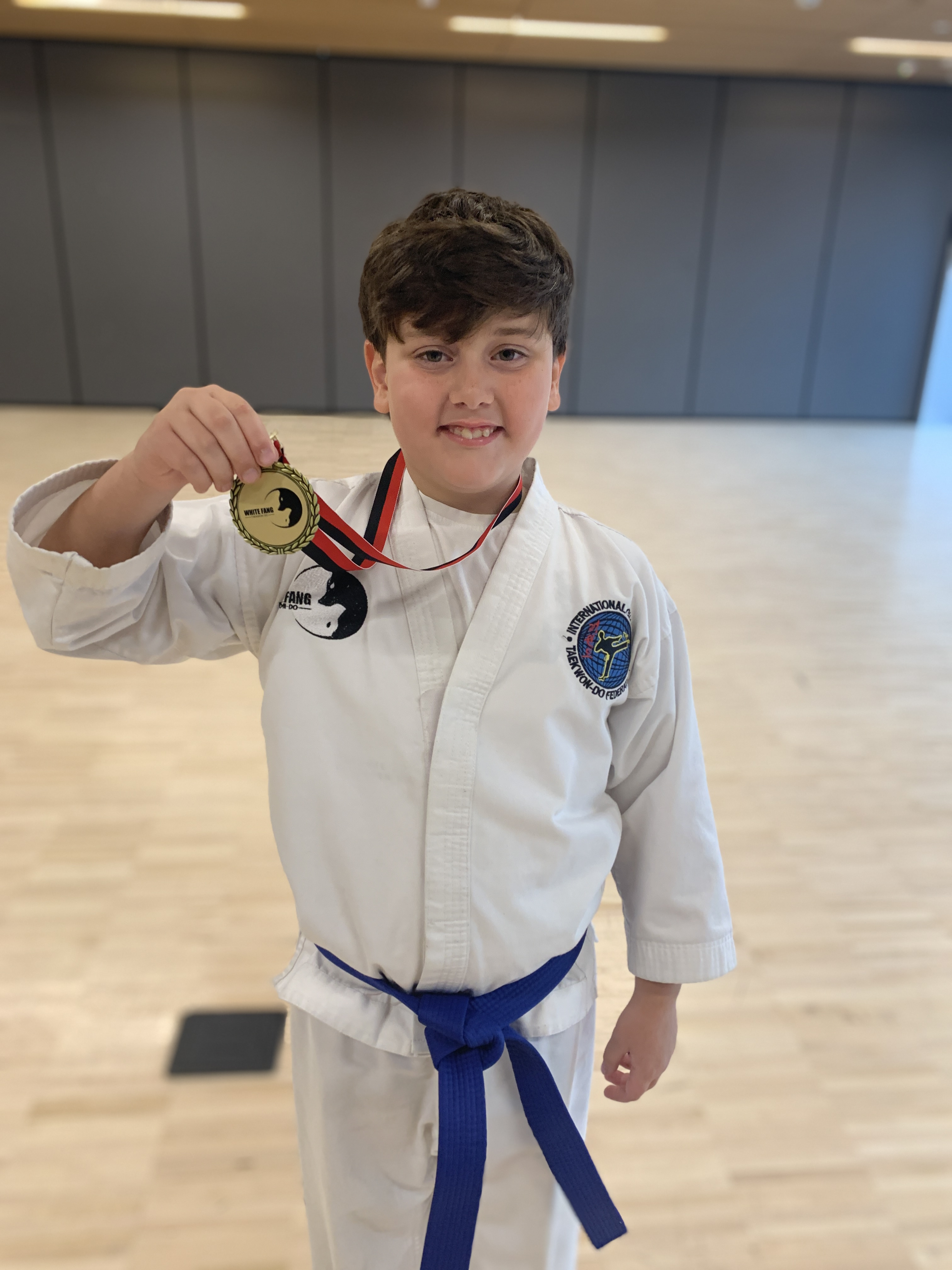Blue belt student holding a Taekwon-Do medal