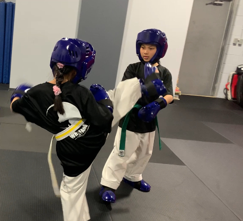 Young students practicing a kicking drill with sparring gear