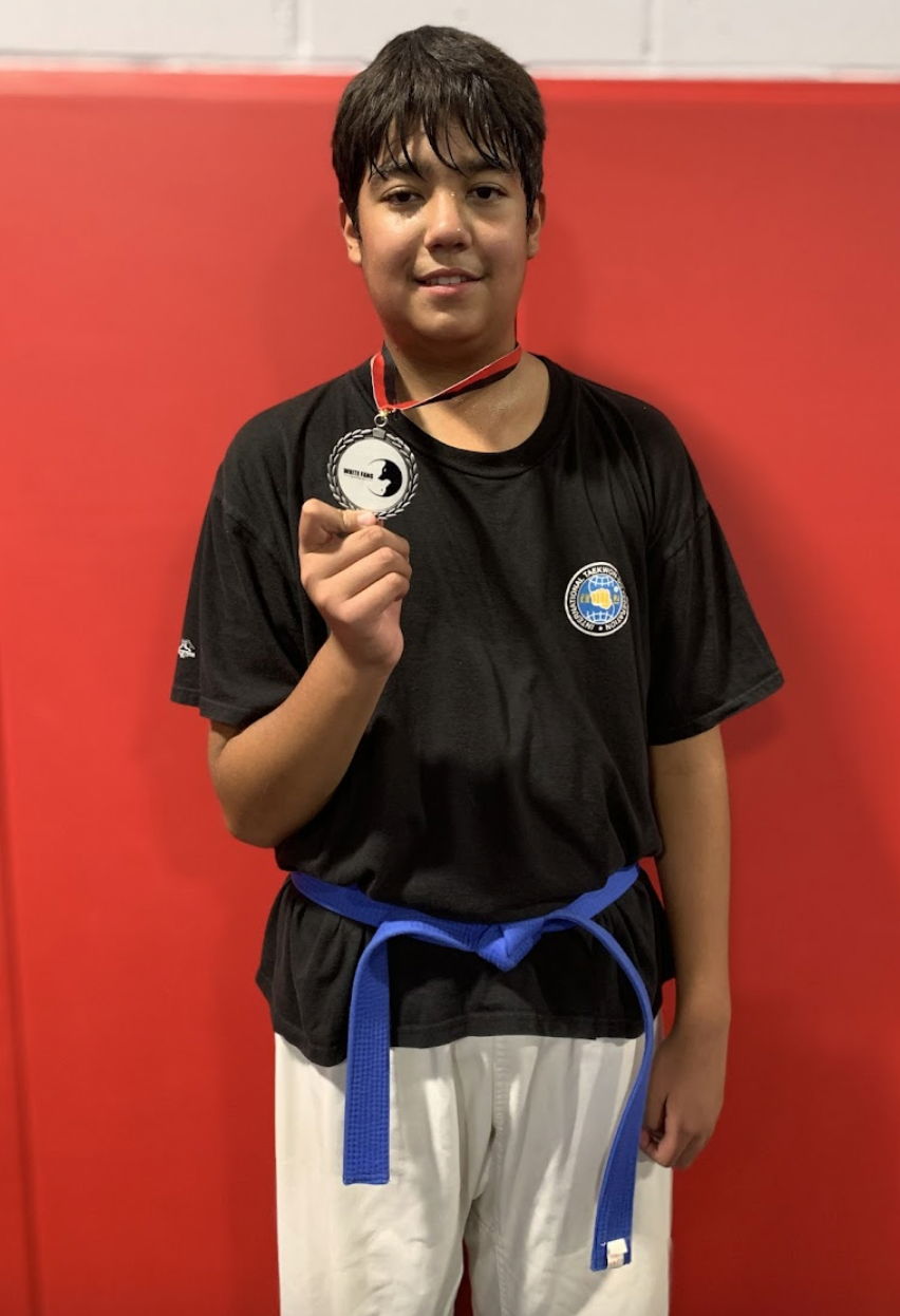 Youth Taekwon-Do student holding a medal after training